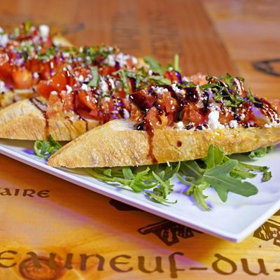Bruschetta topped with tomatoes, greens, and balsamic drizzle.