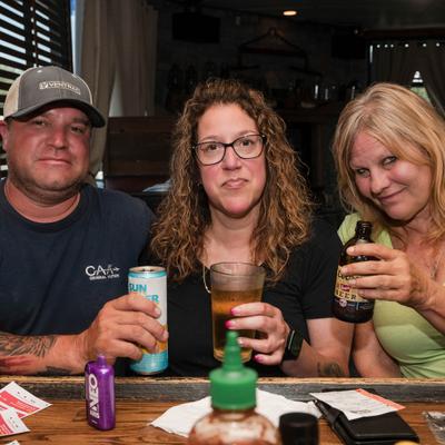 Three people enjoying drinks at the bar counter.