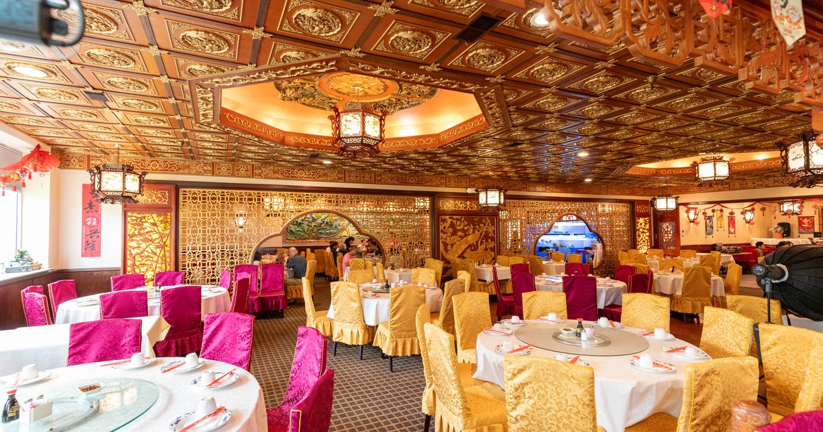 A luxurious interior - ornate wooden ceilings, round tables, white tablecloths, gold and pink chairs