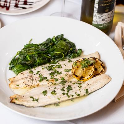 Branzino filet with spinach, herbs, and grilled lemon.