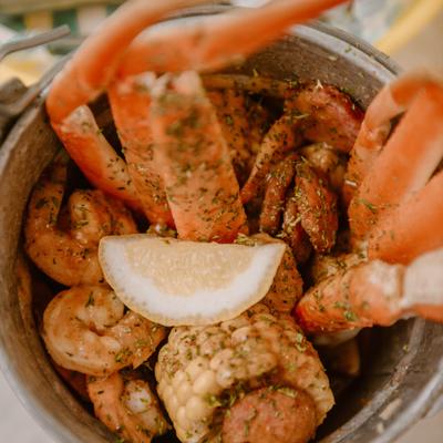 Seafood boil bucket with crab legs, shrimp, and corn on the cob.