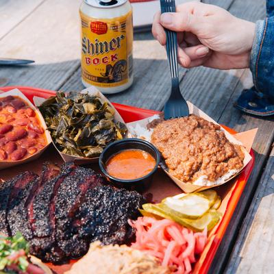 Outdoor dining, a person enjoying beer and food on a BBQ tray.
