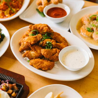 Fried chicken pieces served with dipping sauce, surrounded by assorted dishes.