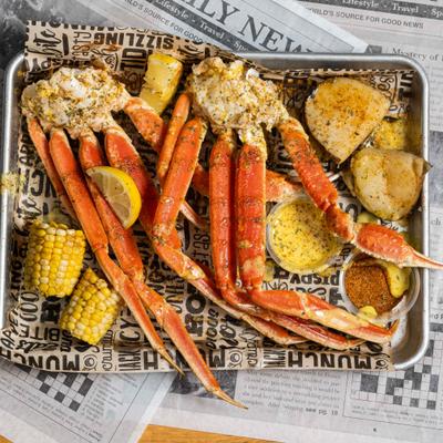 Crab legs with corn, potatoes, lemon wedges, and dipping sauces.