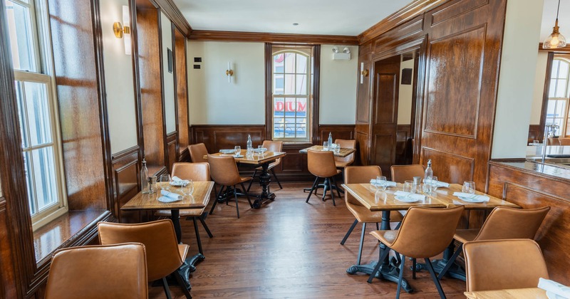 Interior, separate dining area, tables for four and two, ready for guests, wood coated walls