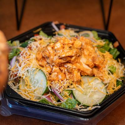 Buffalo Chicken Salad with tomatoes, red onion, cucumber and grated cheese.