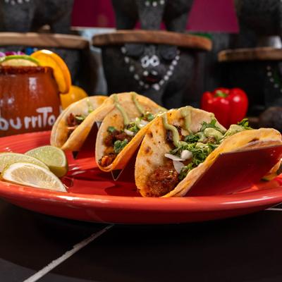 Al Pastor tacos, served with lime wedges.