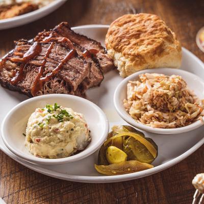 Prime brisket accompanied by coleslaw, potato salad, and a biscuit