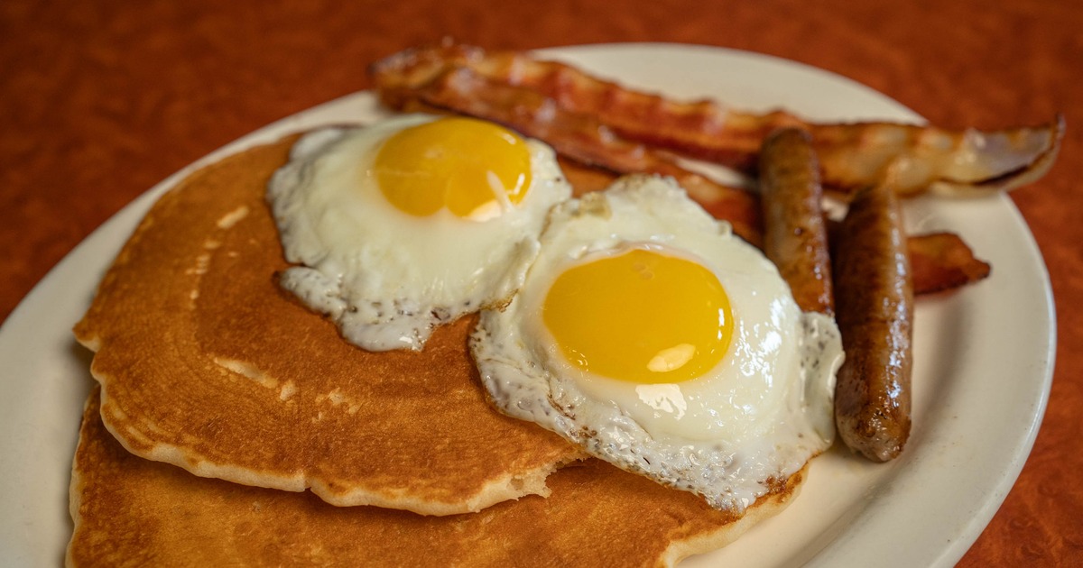 Pancakes with fried eggs, sausages, and bacon strips
