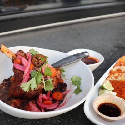 Lamb shank topped with pickled red onions and cilantro, served with sides.