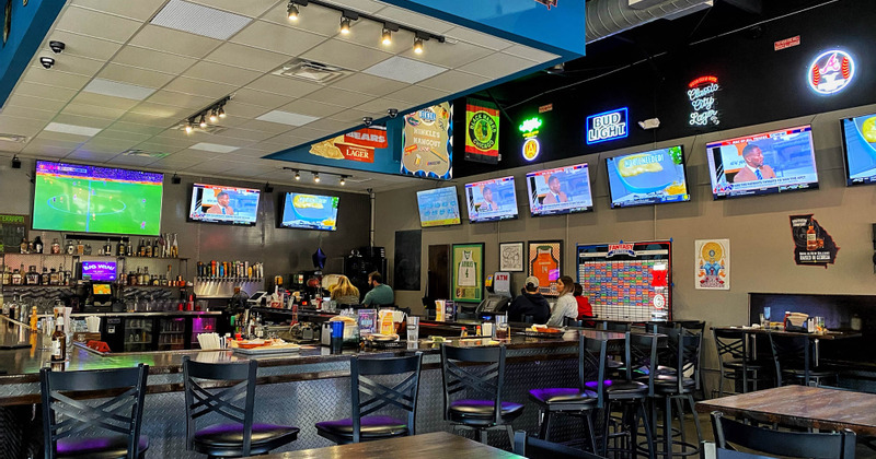 Interior, bar with tall chairs and a bunch of TVs surrounding it