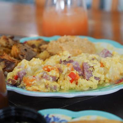 Omelet with ham and peppers, served with grits, roasted potatoes, and a cocktail.