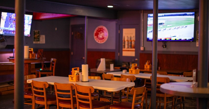 Interior, tables and chairs ready for guests, tv screens on the walls