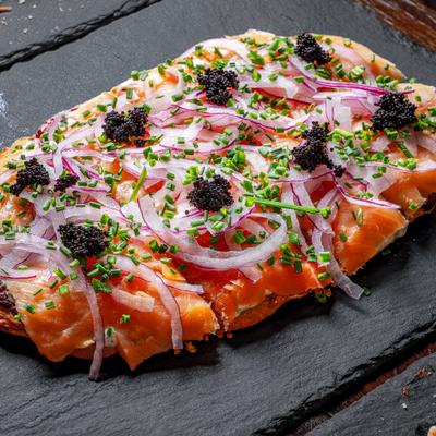 Smoked salmon flatbread, with roasted garlic, cream cheese, red onion, chives, and tobiko.