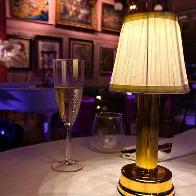 A cup of prosseco on a table, a lamp and art wall.
