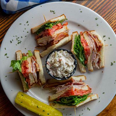 Turkey club with coleslaw and pickle on the side, top view