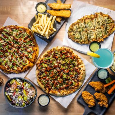 Assortment of pizzas and other dishes served on the table with a cocktail.