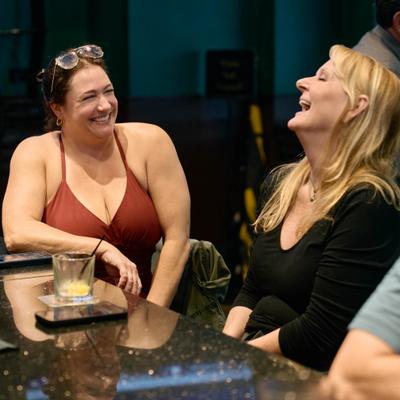 Two guests laughing together at a bar counter.