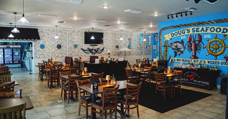 Nautical-themed seafood restaurant interior with wooden tables, blue mural, and nautical decorations