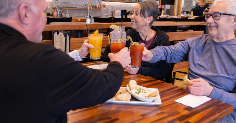 A group of patrons toasting with drinks at a table inside