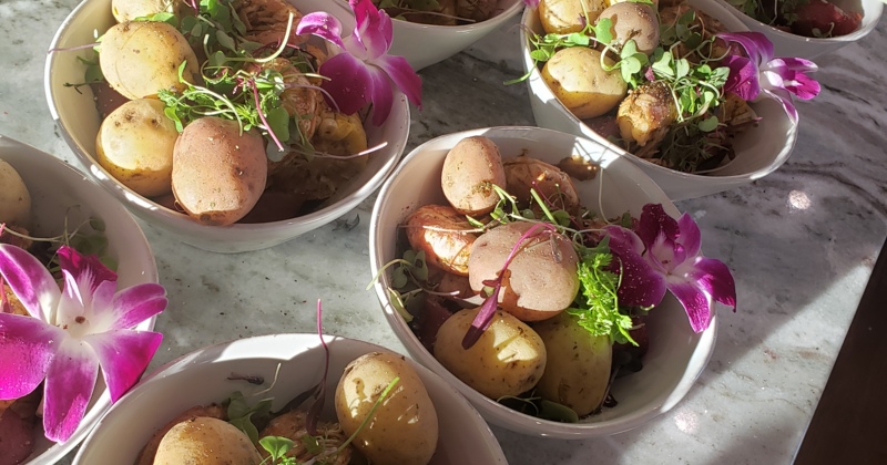 Bowls of potatoes garnished with herbs and purple orchid flowers