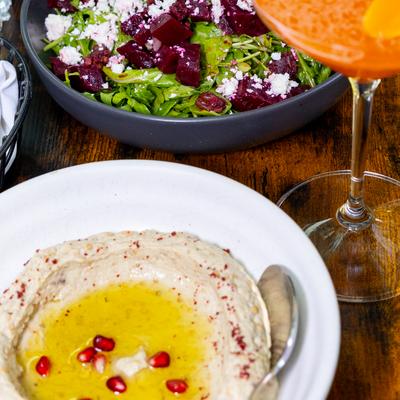 close up of a table with hummus and a salad and a cocktail.
