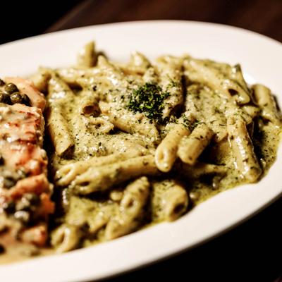 Salmon Piccata with a side of Penne pasta in pesto sauce, close-up.