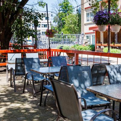 Fenced restaurant patio with light-colored chairs and tables.