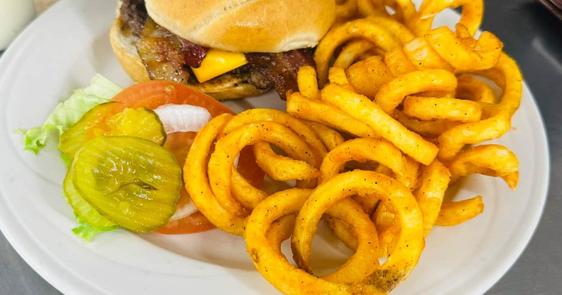 Cheeseburger served with curly fries and pickles