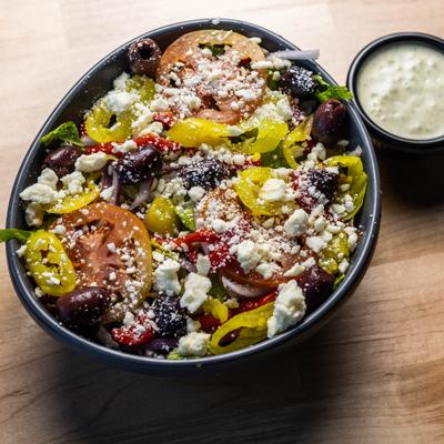 Chopped Greek Salad served on the table with basil tatziki sauce on the side.
