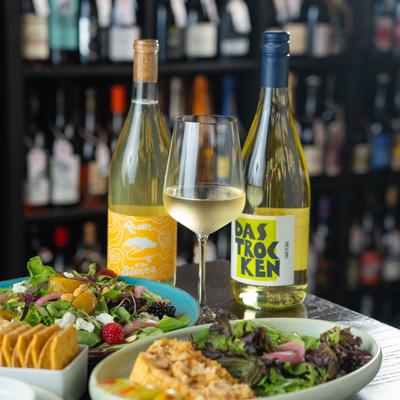 Assorted food plates and white wine.