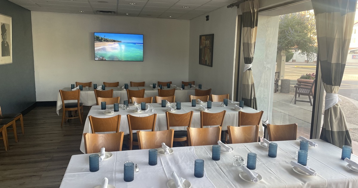 Event room with tables, chairs, place settings and television screen on the wall
