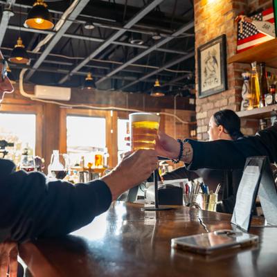 Bartender handing a draft beer to a customer.