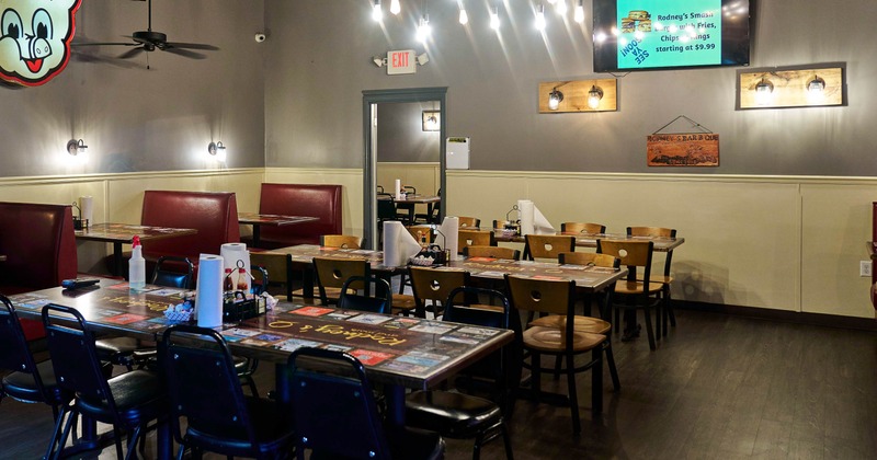 Interior - wooden tables and chairs, pendant lights, red booths and a pig logo on a gray wall