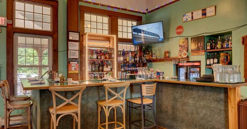 Interior of a bar featuring a wooden counter, colorful liquor bottles on shelves