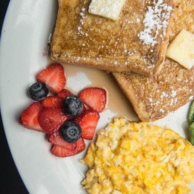 French toast with butter, scrambled eggs, and berries.