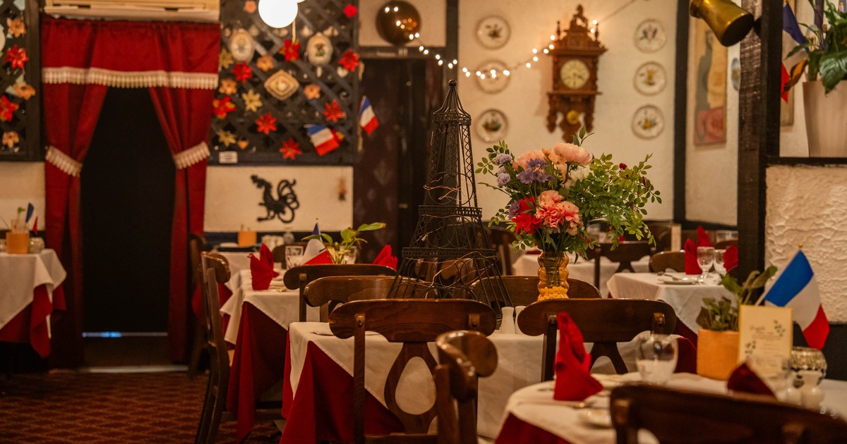 Interior seating area with wooden chairs, vintage posters and decorative plates on wall