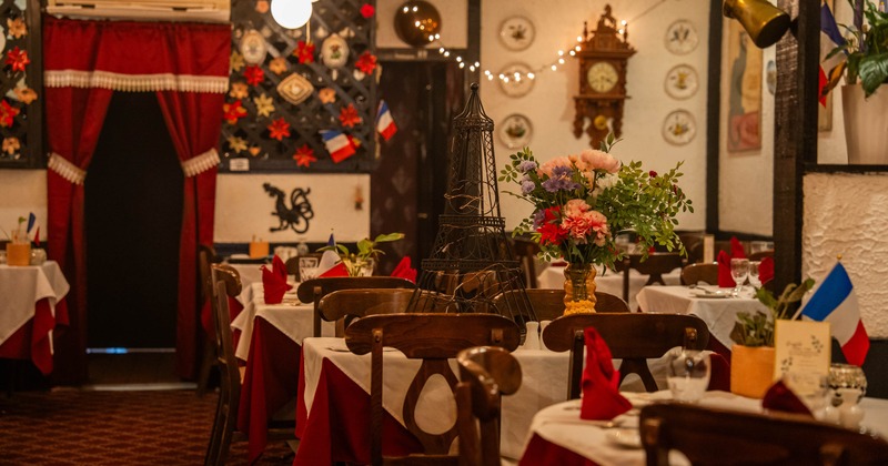 Interior seating area with wooden chairs, vintage posters and decorative plates on wall