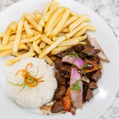 Peruvian stir-fry with marinated sirloin, onions, tomatoes, fries, and rice.