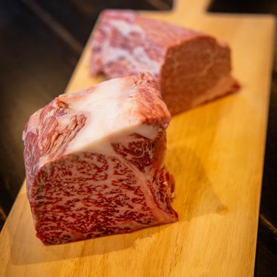 Wagyu filet placed on a wooden board, close up.