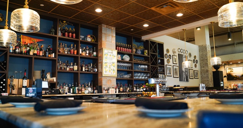 Bar area - stone counter, pendant lights, liquor shelves and decorative wall art.