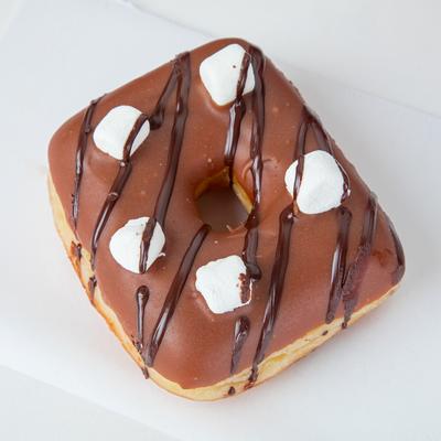 A square donut with chocolate icing, drizzled with chocolate and adorned with marshmallows.