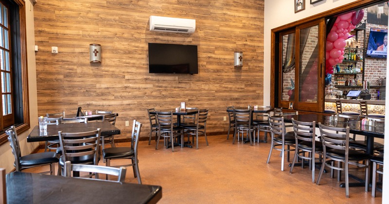 Interior, dining area, tables and chairs ready for guests, TV on the wall