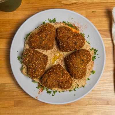 Hart-shaped falafel served on a bed of hummus and garnished with paprika and parsley.