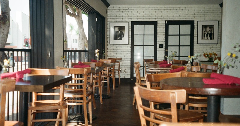 Interior - wooden tables and chairs, red napkins, flower vases & large windows; white brick walls