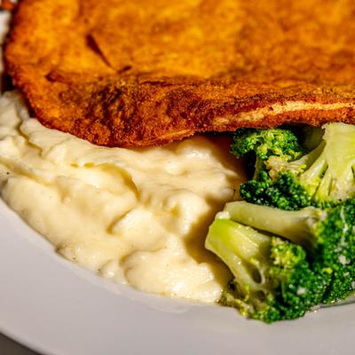 Breaded chicken breast with mashed potatoes and broccoli.