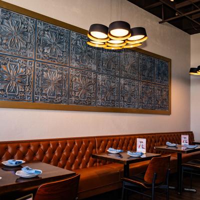 Interior featuring tufted leather seating, set wooden tables, and ornate wall decor.