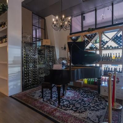 Piano displayed by the wine rack.