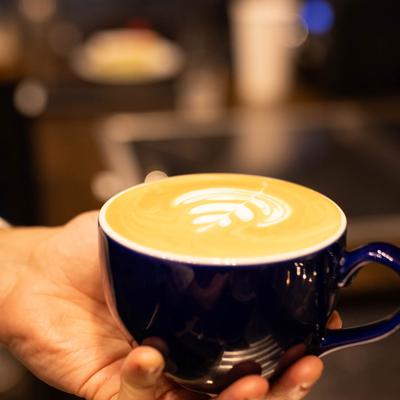 A cup of latte in barista's hand.