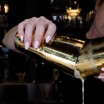 A bartender pouring a drink from shaker.